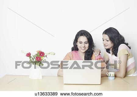 Mid adult woman using a laptop with a young woman beside her View Large Photo Image Stock Photo - Mid adult woman using a laptop with a young woman beside her. Fotosearch