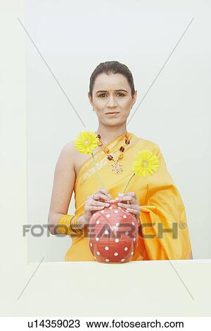 Stock Image - Portrait of a young woman holding a flower pot. Fotosearch