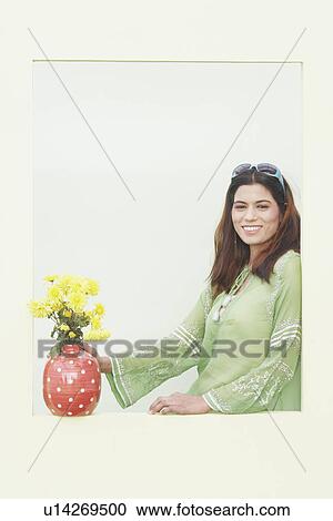Stock Image - Portrait of a young woman standing near a window. Fotosearch