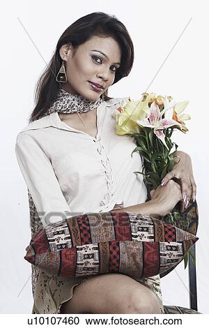 Portrait of a young woman with a cushion on her lap sitting on a chair View Large Photo Image Stock Image - Portrait of a young woman with a cushion on her lap sitting on a chair. Fotosearch