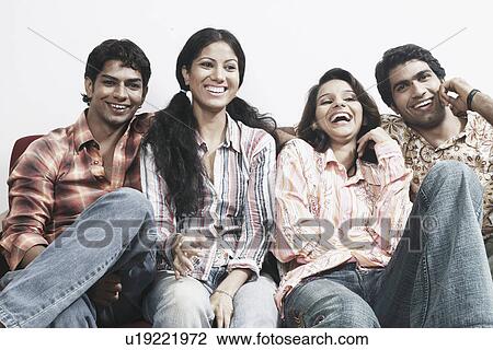 Close-up of two young couples sitting together on a couch smiling View Large Photo Image Stock Image - Close-up of two young couples sitting together on a couch smiling. Fotosearch
