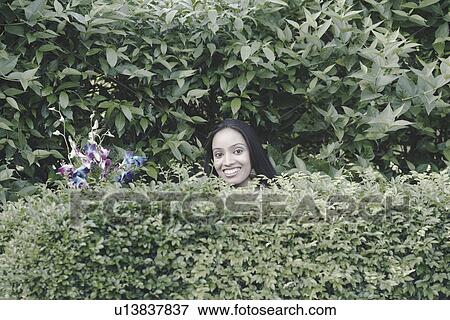 Stock Photo - Portrait of a teenage girl standing in a garden and smiling. Fotosearch