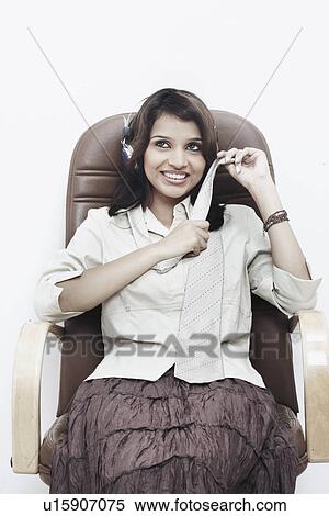 Stock Photography - Businesswoman wearing headphones sitting on an office chair. Fotosearch