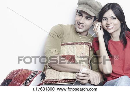 Stock Image - Close-up of a young couple sharing a headphone. Fotosearch