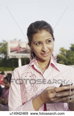 Stock Photo - Close-up of a young woman listening to an MP3 player. Fotosearch