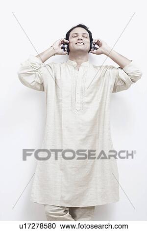 Stock Image - Mid adult man wearing headphones listening to music. Fotosearch