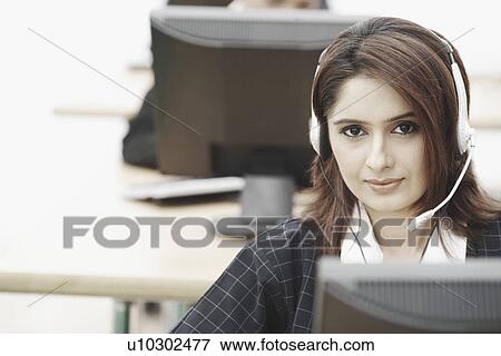Stock Photo - Portrait of a businesswoman wearing a headset sitting in front of a computer. Fotosearch