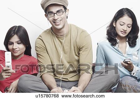 Stock Photo - Portrait of a young man sitting between two young women. Fotosearch