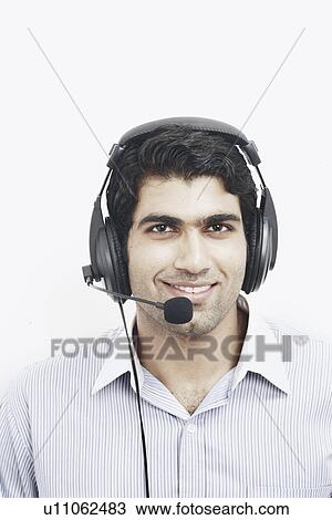 Stock Image - Portrait of a young man wearing a headset smiling. Fotosearch