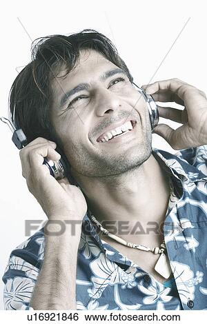 Young man wearing headphones listening to music View Large Photo Image Stock Photograph - Young man wearing headphones listening to music. Fotosearch