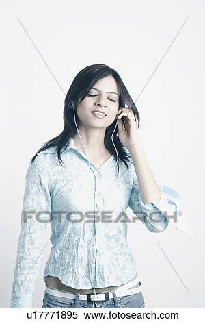 Stock Photography - Young woman listening to music wearing headphones. Fotosearch