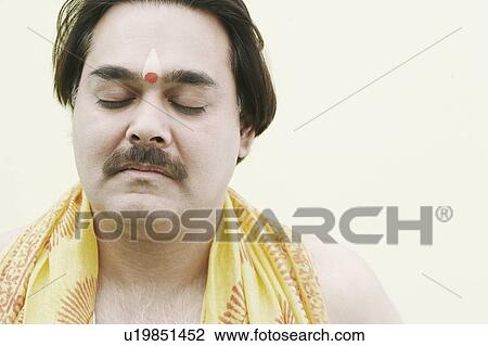 Stock Image - Close-up of a priest praying with his eyes closed. Fotosearch