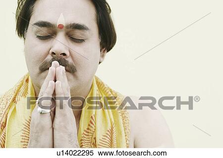 Stock Photography - Close-up of a priest praying with his eyes closed. Fotosearch