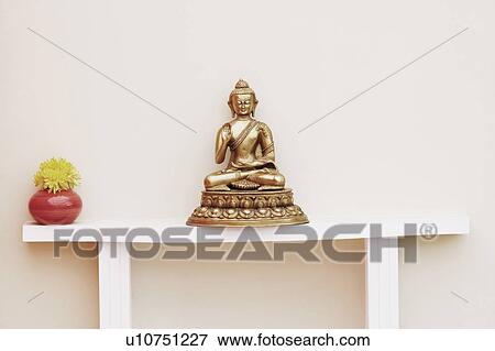 Stock Photo - Close-up of a statue of Buddha and a flower vase. Fotosearch
