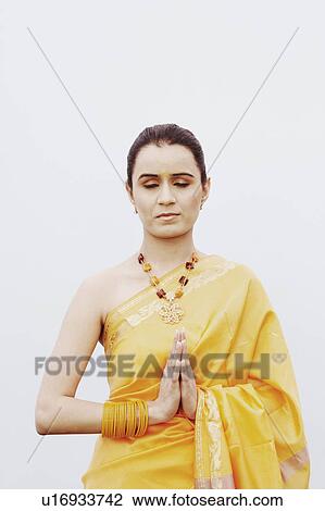 Stock Image - Close-up of a young woman standing in a prayer position. Fotosearch