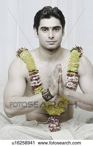 Stock Image - Portrait of a young man sitting in a prayer position. Fotosearch