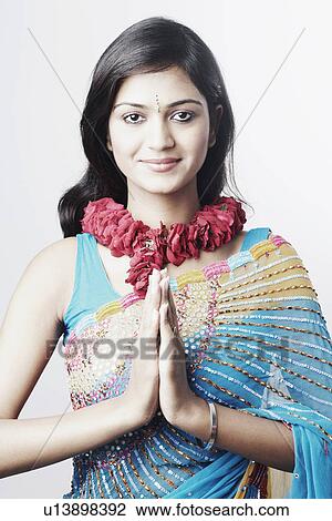 Stock Image - Portrait of a young woman in a prayer position wearing a garland. Fotosearch