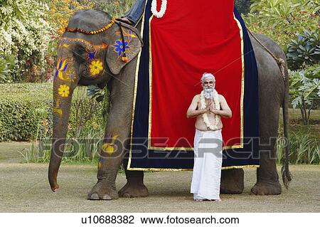 Priest standing in a prayer position beside an elephant View Large Photo Image Stock Image - Priest standing in a prayer position beside an elephant. Fotosearch
