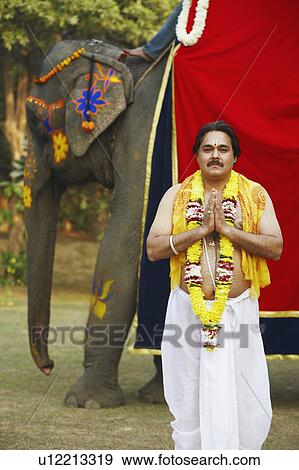 Priest standing in a prayer position beside an elephant View Large Photo Image Stock Photo - Priest standing in a prayer position beside an elephant. Fotosearch