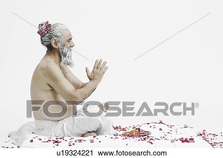 Stock Image - Side profile of a priest sitting in a prayer position. Fotosearch