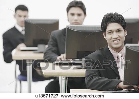Businessmen working on computers in an office View Large Photo Image Stock Photo - Businessmen working on computers in an office. Fotosearch