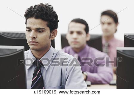Businessmen working on computers in an office View Large Photo Image Stock Photo - Businessmen working on computers in an office. Fotosearch