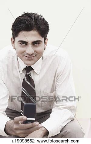 Stock Image - Portrait of a businessman holding a mobile phone. Fotosearch