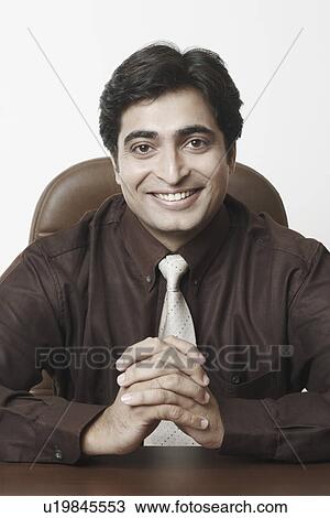Portrait of a businessman sitting with his hands clasped View Large Photo Image Stock Image - Portrait of a businessman sitting with his hands clasped. Fotosearch