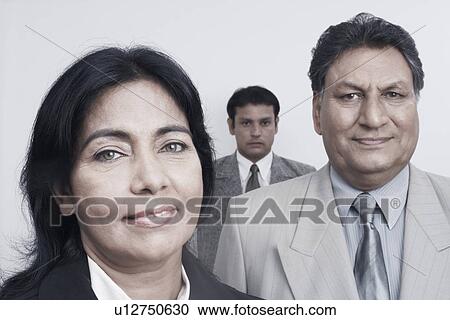 Stock Image - Portrait of a businesswoman and two businessmen behind her. Fotosearch