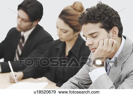Stock Photo - Businessmen sitting in a conference room with his eyes closed. Fotosearch