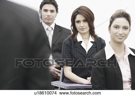 Picture - Portrait of two businesswomen sitting with a businessman. Fotosearch