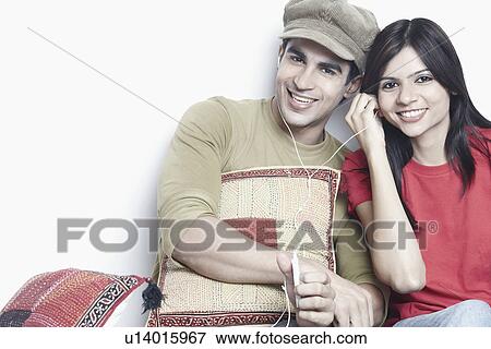 Stock Photo - Close-up of a young couple listening to music wearing headphones. Fotosearch