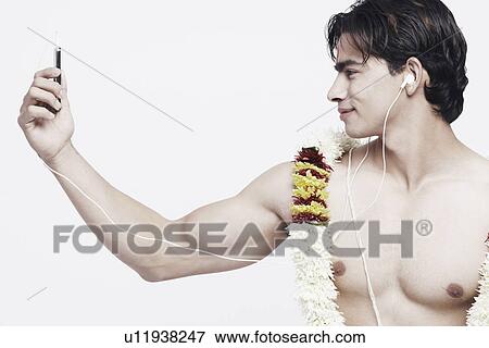 Close-up of a young man listening to an MP3 player View Large Photo Image Stock Photo - Close-up of a young man listening to an MP3 player. Fotosearch