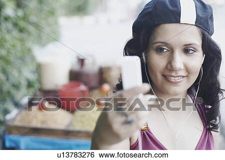 Stock Photograph - Close-up of a young woman listening to an MP3 player. Fotosearch