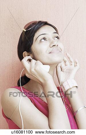 Stock Image - Close-up of a young woman wearing earphones listening to music. Fotosearch