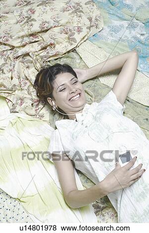 High angle view of a young woman listening to an MP3 player View Large Photo Image Stock Photo - High angle view of a young woman listening to an MP3 player. Fotosearch