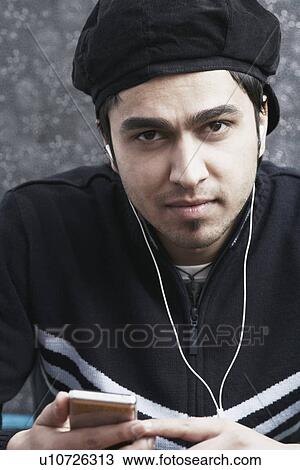 Stock Image - Portrait of a young man listening to an MP3 player. Fotosearch