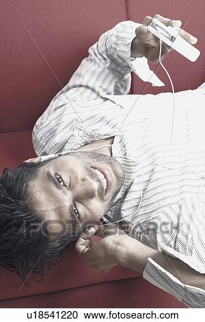 Portrait of a young man listening to an MP3 player View Large Photo Image Stock Image - Portrait of a young man listening to an MP3 player. Fotosearch