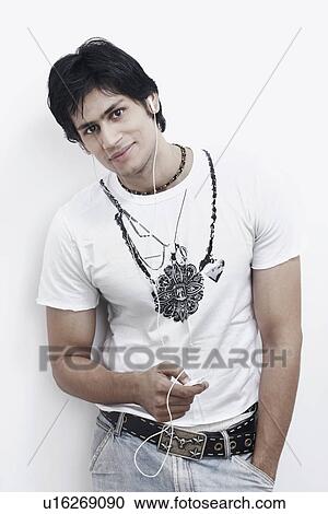 Stock Image - Portrait of a young man wearing earphones listening to music. Fotosearch