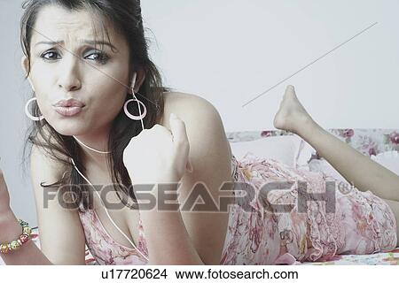 Portrait of a young woman wearing earphones listening to music View Large Photo Image Picture - Portrait of a young woman wearing earphones listening to music. Fotosearch