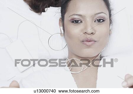 Portrait of a young woman wearing earphones listening to music View Large Photo Image Stock Image - Portrait of a young woman wearing earphones listening to music. Fotosearch