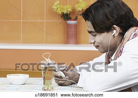 Stock Image - Side profile of a young man listening to an MP3 player. Fotosearch