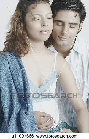 Stock Photograph - Young couple wearing headphones listening to music. Fotosearch