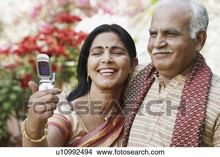 Picture - Close-up of a mature couple looking at a mobile phone. Fotosearch