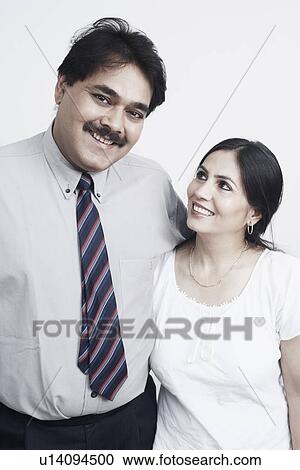 Stock Image - Close-up of a mature couple with arms around smiling. Fotosearch