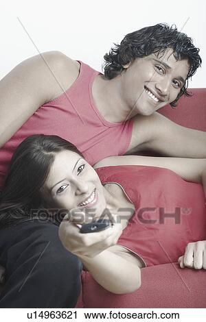 Stock Image - Portrait of a young couple lying on a couch. Fotosearch