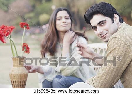 Stock Photography - Portrait of a young couple sitting in a garden. Fotosearch