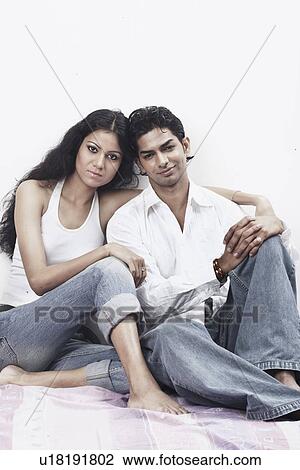 Stock Image - Portrait of a young couple sitting together on the floor. Fotosearch