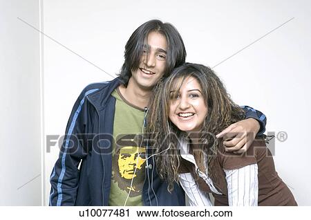 Stock Image - Portrait of a young couple with their arms around each other. Fotosearch