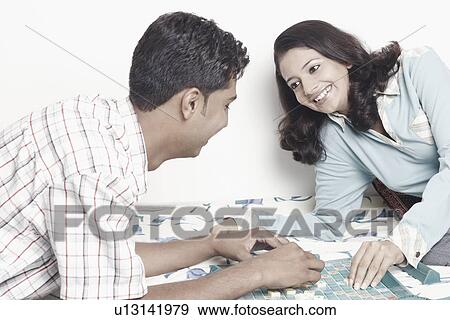 Stock Photo - Side profile of a young couple playing scrabble. Fotosearch